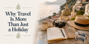 A notebook, camera, photos, and straw hat rest on a stone ledge overlooking a coastal town. Text reads: Why Travel Is More Than Just a Holiday.