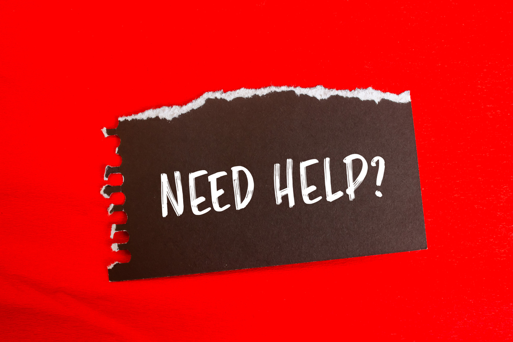 A torn piece of black paper with NEED HELP? written in white text sits on a bright red background.