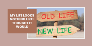 Two wooden signs point in opposite directions, labelled Old Life in red and New Life in green. A text box says, My life looks nothing like I thought it would.