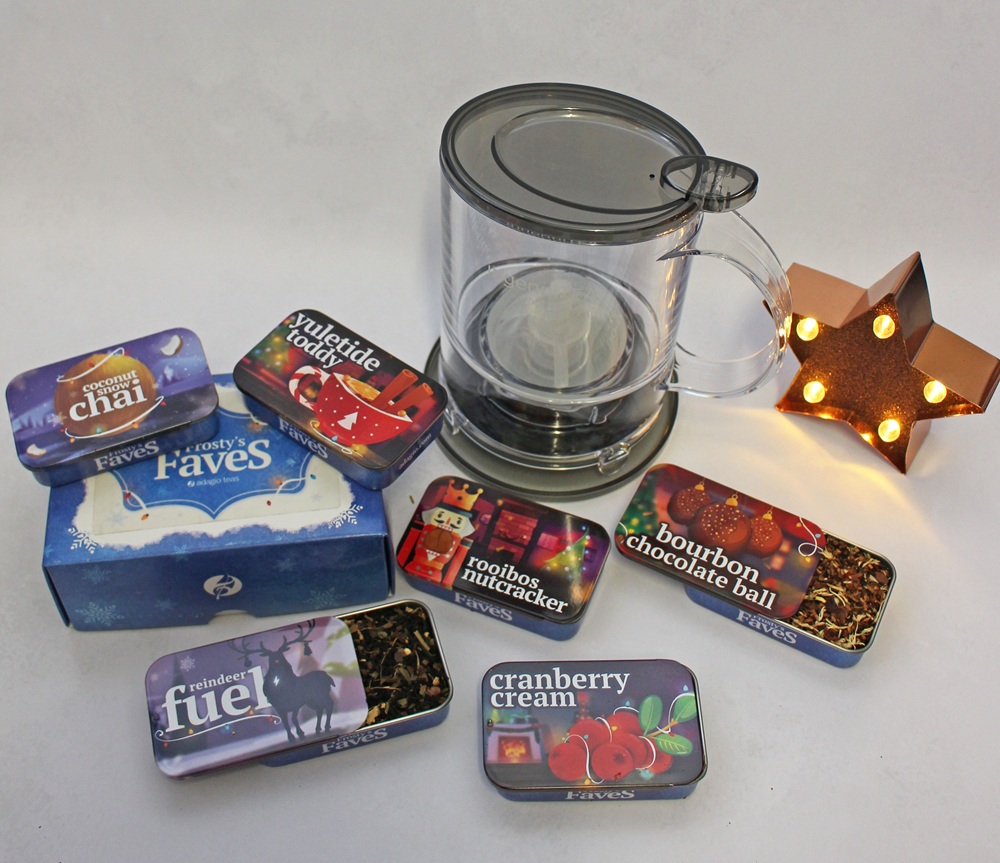 Adagio Teas Frosty's Favourites collection featuring five assorted tea tins, a tea infuser mug, and a decorative lit star.