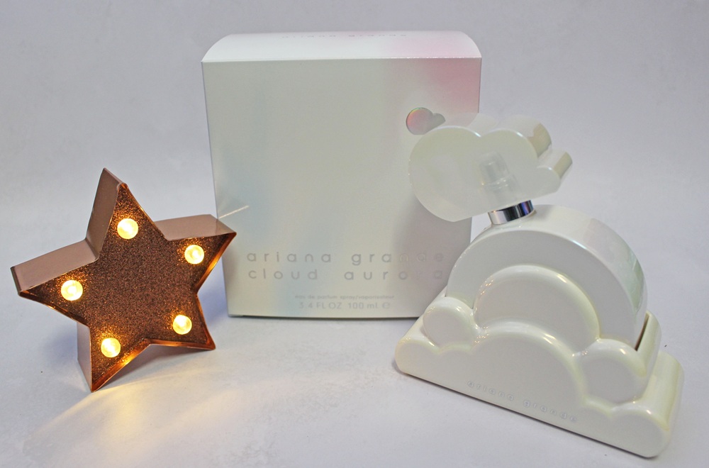 Ariana Grande Cloud Aurora perfume bottle and box, next to a small, illuminated star-shaped light.