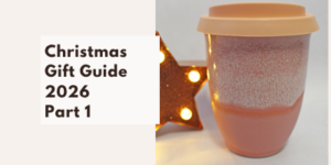 Text reading Christmas Gift Guide 2026 Part 1 next to a pink ceramic travel mug and a lit star-shaped ornament.