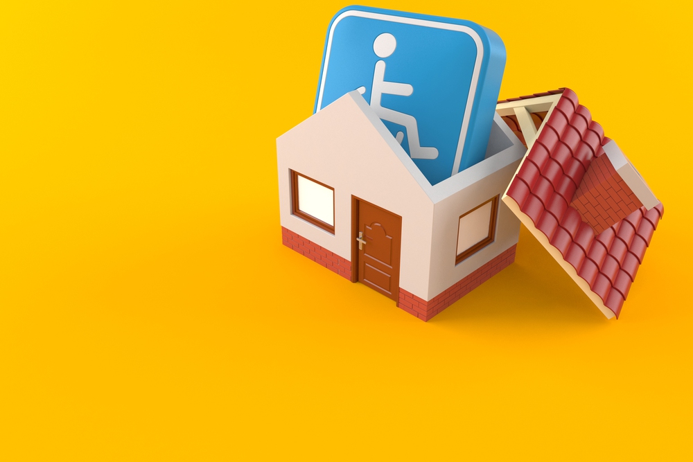A small model house with its roof off, containing a large blue accessibility icon on a yellow background.