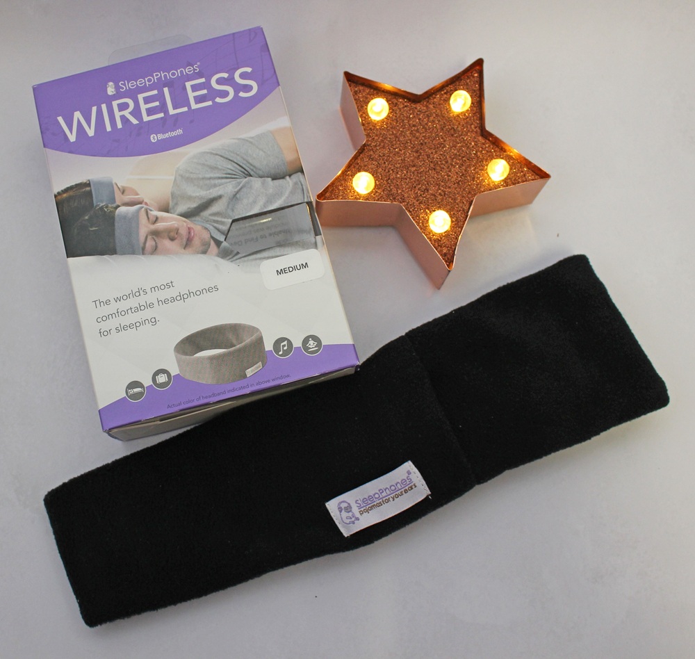 SleepPhones wireless headband packaging next to the black headband and a star-shaped light.