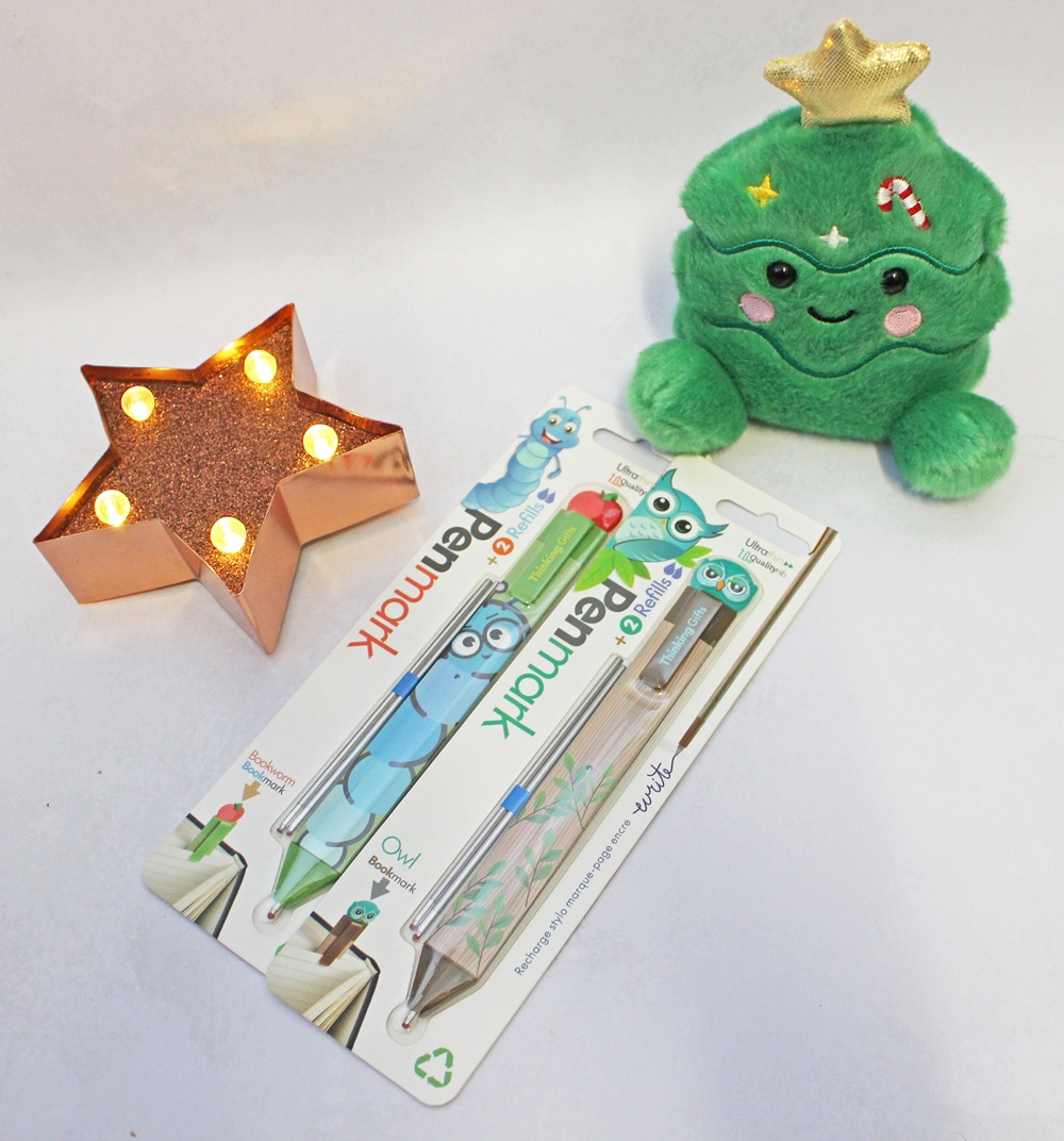 A packet of two Penmark pens with refills, next to a gold star-shaped light and a plush Christmas tree character.