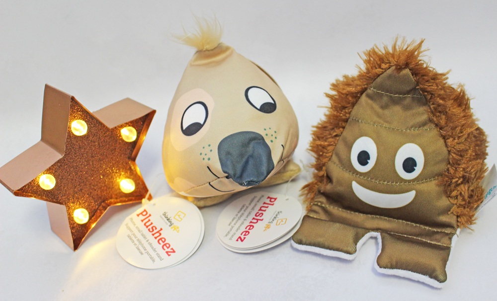 Two plush phone stands shaped like a sloth and a smiling creature next to a glowing star-shaped light.