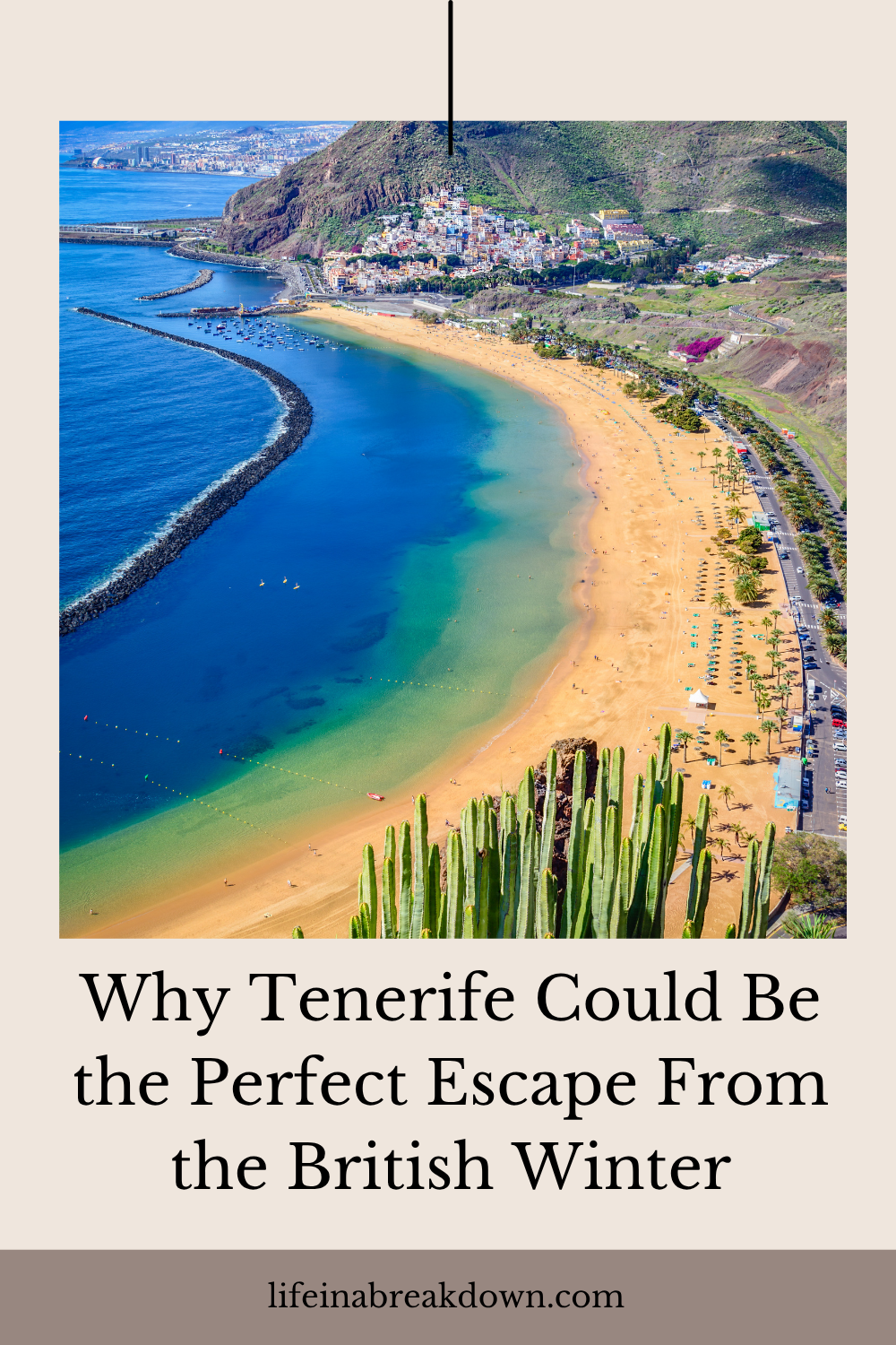 Aerial view of a curved sandy beach and turquoise sea in Tenerife, with a town nestled at the base of coastal mountains.