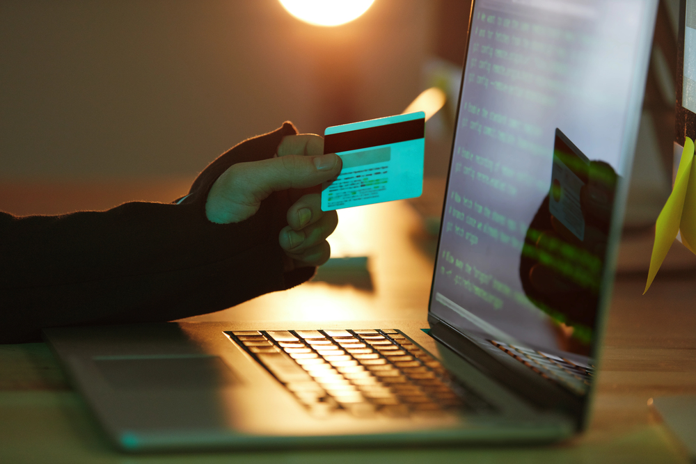A person holding a credit card whilst using a laptop.