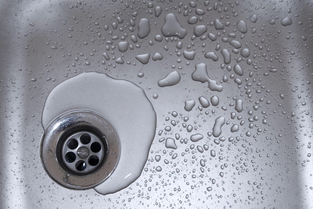 Water droplets on a stainless steel kitchen sink bowl.